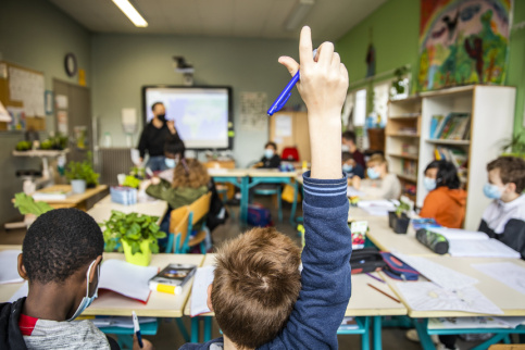 Un jeune en classe qui lève la main pour intervenir. 