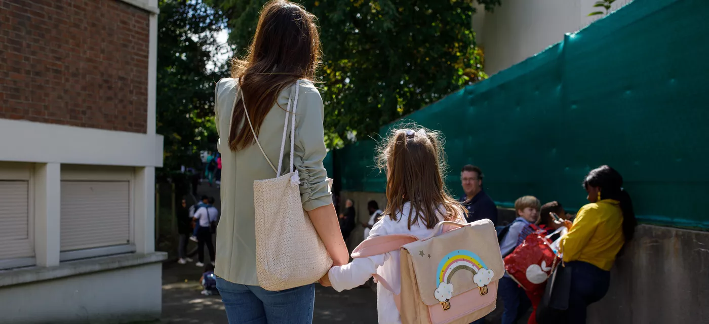 Une maman et sa fille dans la cour de récréation, de dos