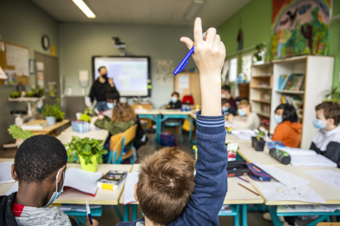 Un enfant qui lève le doigt pour participer en classe.